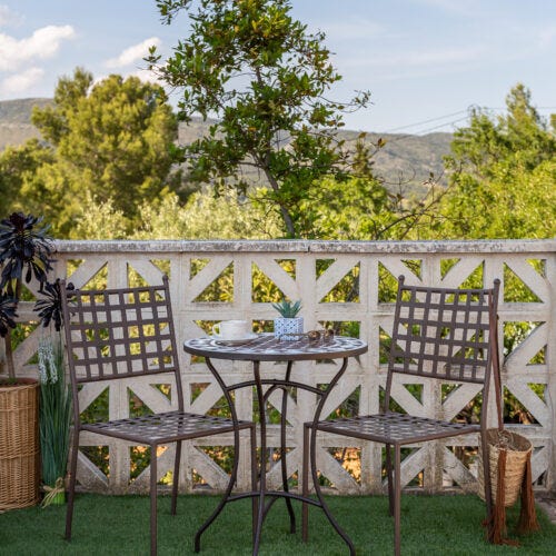 Conjunto de hierro forjado en terraza pequeña con cesped y paisaje natural