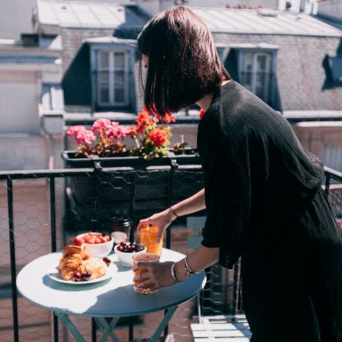 Chica desayunando en su terraza pequeña