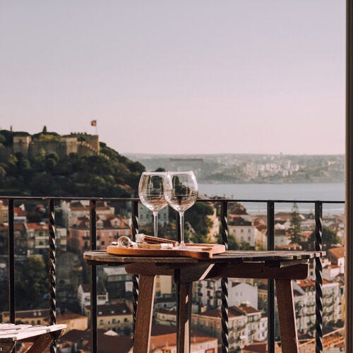 Balcon con mesa de exterior y dos copas de vino con paisaje