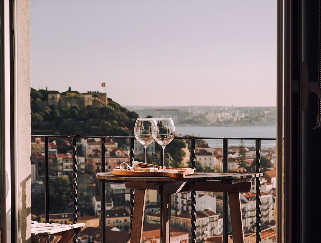 Balcon con mesa de exterior y dos copas de vino con paisaje