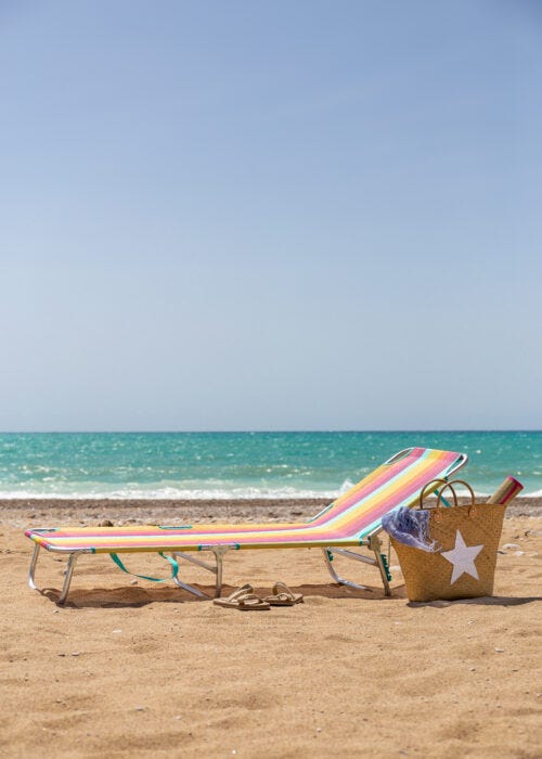 Tumbona de playa inclinable multicolor en la arena para tomar el sol