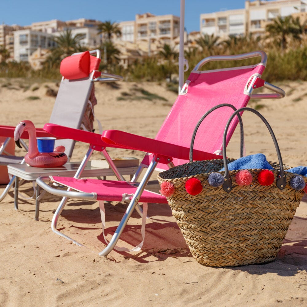 Sillas de playa y capazos en la arena con mesita