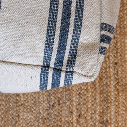 Detalle de puff de rayas marinero sobre alfombra trenzada