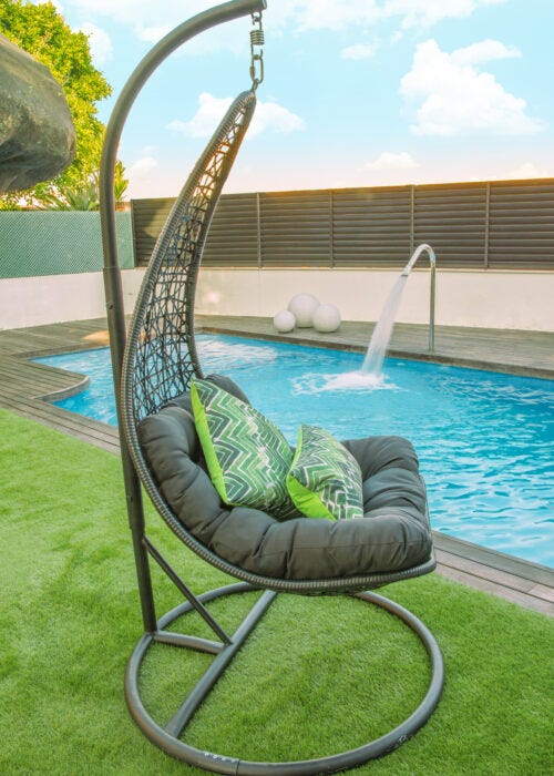 Silla colgante negra en jardin con piscina