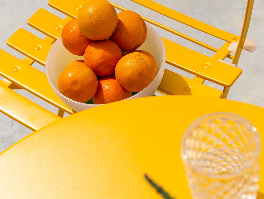 Silla y mesa de exterior con naranjas para decoracion mas alegre