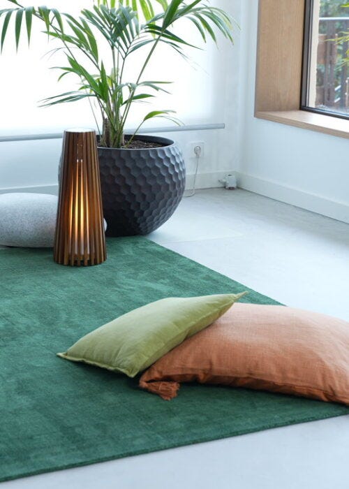 alfombra verde con cojines neutros
