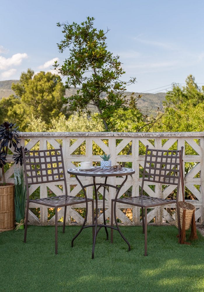 Conjunto de hierro forjado en terraza pequeña con cesped y paisaje natural